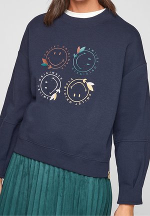 Sweatshirt navy avec des manches surdimensionnées, mettant en avant quatre visages souriants colorés dans des cercles avec des feuilles. Poignets et ourlet côtelés.