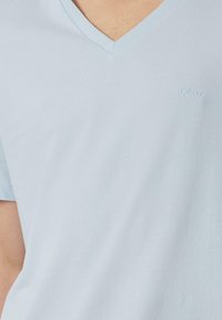 Lichtblauwe V-hals t-shirt gemaakt van zacht materiaal, met korte mouwen en een klein, geborduurd logo op de borst.