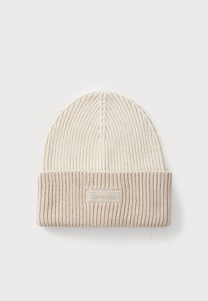 Beige strikket lue med brettbar ribbestrikket kant, som har et textured mønster og et merke med "Calvin Klein" i en rektangulær lapp.