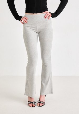 Graue ausgestellte Leggings aus weichem Jersey-Stoff, mit einem hohen Bund. Kombiniert mit schwarzen Schuhen mit Absätzen, die mit Schleifen und Perlen verziert sind.