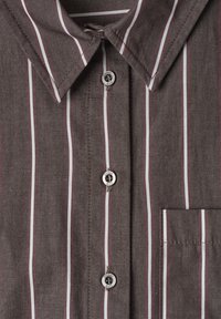 Chemise marron à boutons avec rayures verticales blanches et bordeaux, poche avant et texte "street one" sur les boutons.