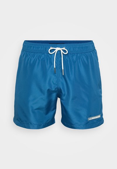 Pantaloni da bagno blu realizzati in tessuto morbido, con una vita elastica e cordoncino bianco, e una toppa con logo sul lato inferiore.