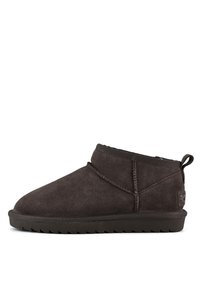 Bottines en daim marron avec un bout arrondi, des coutures minimales et une semelle en caoutchouc texturée. Équipées d'une languette à l'arrière.