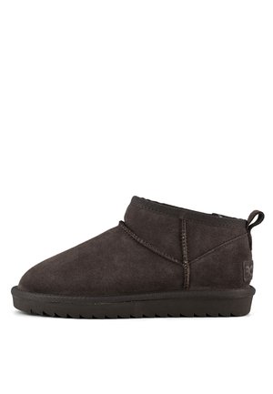 Bottines en daim marron avec un bout arrondi, des coutures minimales et une semelle en caoutchouc texturée. Équipées d'une languette à l'arrière.