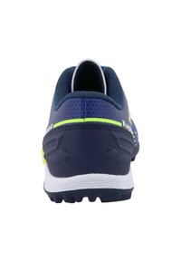 Sportskor i mörkblått med neongröna accenter och en texturerad baksida, som visar en låg profil och en vit sula.