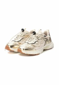 Zapatillas deportivas beige con acentos metálicos dorados, parte superior de malla, tejido texturizado, suela de goma y cordones elásticos para un ajuste seguro.