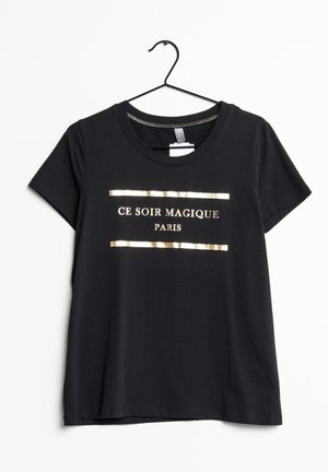Zwarte kortebloezers T-shirt aan een hanger met gouden tekst "CE SOIR MAGIQUE PARIS" omrand door twee horizontale gouden lijnen aan de voorkant.