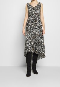 Vestido de estampado de leopardo con escote en V, botones en la parte delantera y dobladillo asimétrico. Hecho de tela suave, combinado con botas negras hasta la rodilla.