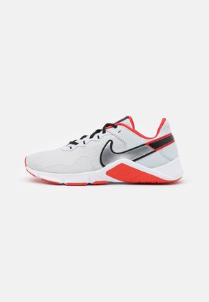 Baskets Nike blanches et rouges avec des lacets noirs et le logo argenté, vues de côté sur un fond blanc uni.