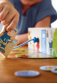 Holzspielzeug, das eine Feuerwehrmannfigur in Blau und Gelb zeigt, die aus einer bunten Box mit verschiedenen illustrierten Mustern und Formen gezogen wird.