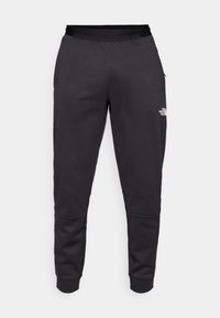 Čierne tepláky vyrobené z hladkej látky, s priliehavým strihom, elastickým pásom a detailom loga na pravej nohe.
