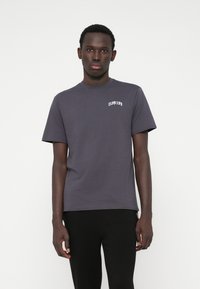 T-shirt de manga curta masculina em algodão cinza escuro, com uma pequena gráfica branca no peito, decote redondo e um corte clássico.