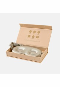 Silkkatsouni unipanta vaaleassa kullassa, jossa on silmäaukot, pakattuna beigeen laatikkoon, jossa on kuvakkeita, jotka kuvaavat tuotteen ominaisuuksia ja hoito-ohjeita.