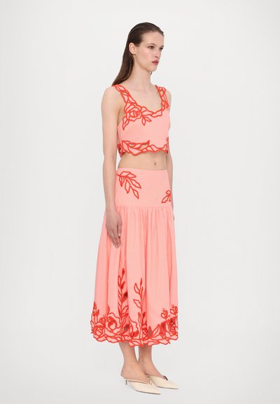 Zweiteiliges Korallen-Outfit mit einem bauchfreien Oberteil, das am Rand mit floraler Stickerei verziert ist, und einem passenden Rock mit Raffung.