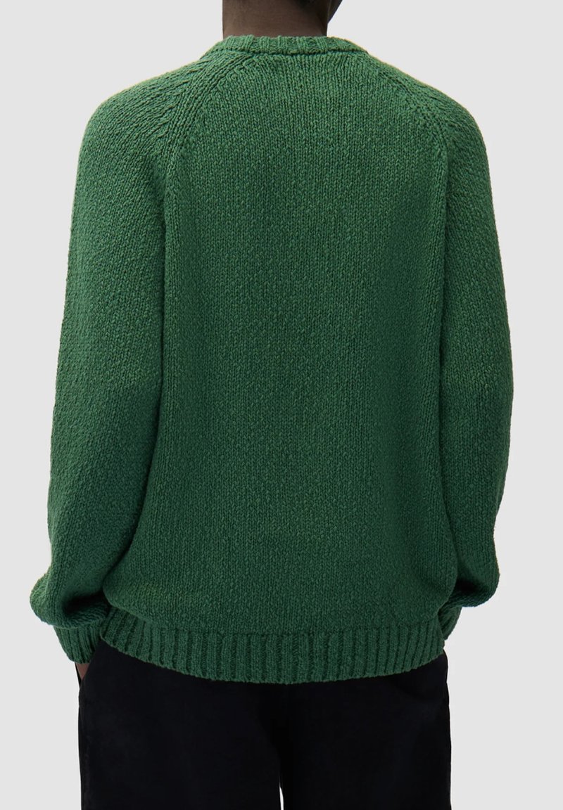 Maglione verde lavorato a maglia con finitura testurizzata, scollo rotondo e orlo a coste. Vestibilità ampia con maniche lunghe e cuciture raglan.