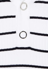 Tessuto a coste bianco con strisce nere orizzontali, caratterizzato da un anello argentato a loop sullo scollo. Design semplice e strutturato.