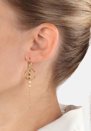 Pendientes de aro de oro con un diseño circular que presenta una cadena colgante y acentos de cuentas, exhibiendo una textura metálica suave.