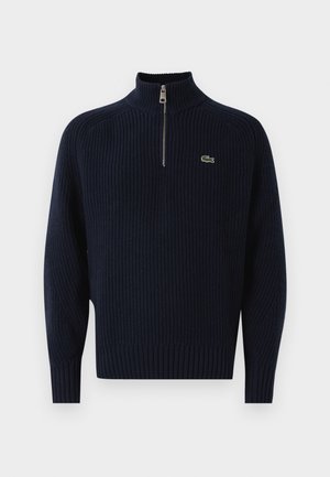 Pullover lavorato a maglia blu navy con colletto a mezza zip, dotato di polsini e orlo a coste, e un piccolo logo di coccodrillo verde sul petto.