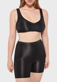 Schwarzer nahtloser Bralette mit breiten Trägern und V-Ausschnitt, kombiniert mit passenden hoch taillierten Shorts, die beide eine glatte Textur aufweisen.