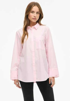 Chemise rose clair à manches longues avec col, boutonnée sur le devant et une poche poitrine unique ; présente une texture lisse et une coupe décontractée.
