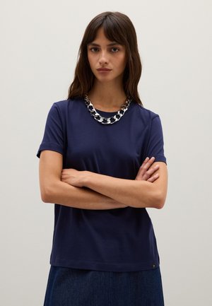 Marineblauw t-shirt met korte mouwen, gemaakt van een zachte, gladde stof. Heeft een ronde halslijn en een imposante zilveren ketting als accent.