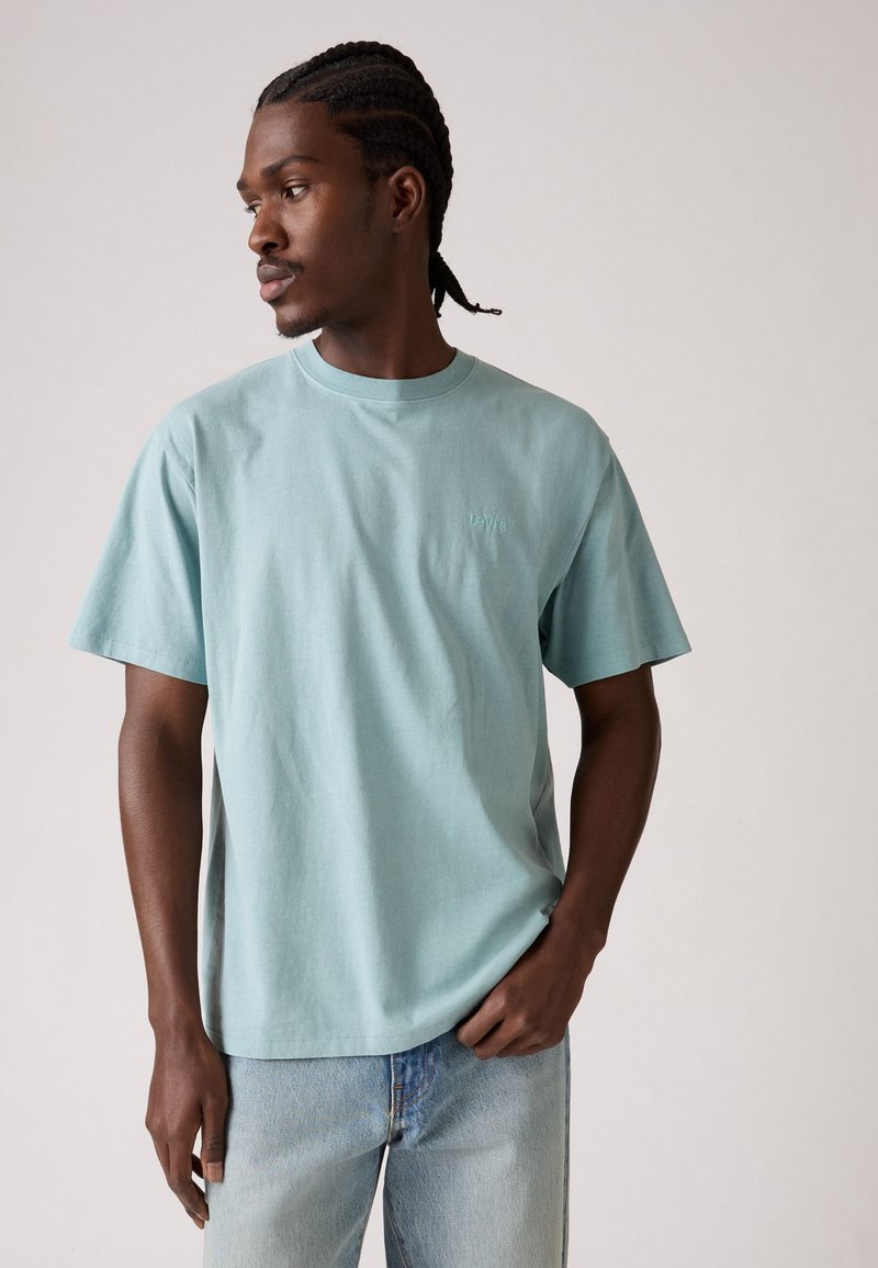 Lyseblå bomulds T-shirt med rund hals og korte ærmer. Har et lille, diskret broderet logo på brystet. Bæres med lyse denim jeans.