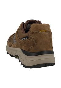 Brauner Wildleder-Wanderschuh mit gepolstertem Kragen, schwarzer Gummisohle und verstärkter Zwischensohle. Mit gelben Akzenten nahe der Ferse und Logo-Detail.