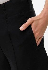 Zwarte broeken met een gladde textuur, voorzien van een zijzak en een aangesloten ontwerp. De stof lijkt duurzaam en licht gestructureerd.