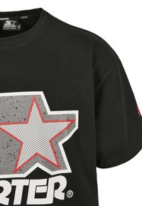 Černé bavlněné tričko s velkým šedým grafickým vzorem hvězdy a červenými a bílými akcenty, včetně výrazného nápisu "STARTER".