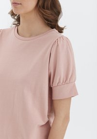 Rosa Bluse mit kurzen Ärmeln, rundem Ausschnitt und Puffärmeln aus weichem Stoff. Glatte Textur und lockere Passform.