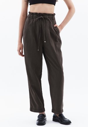 Pantalons marron taille haute avec une ceinture élastique et un cordon de serrage, présentant une coupe décontractée et des poches latérales. Texture de tissu lisse.