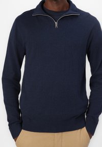 Mörkblå kvartdragare i mjukt stickat material, med ribbad krage och mudd, samt en slät textur och klassisk passform.