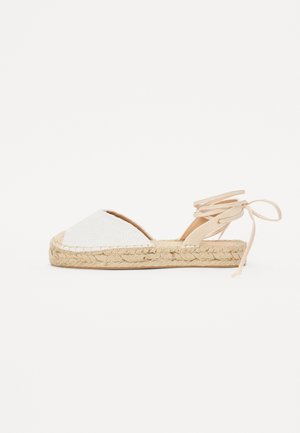 Hvid espadrillesandal med vævet juttesål og ankelstropper på en ensartet hvid baggrund.