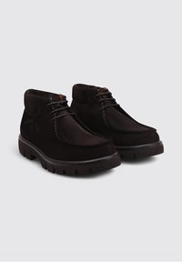 Botas de tobillo de ante marrón con puntera redondeada, diseño con cordones y suela de goma gruesa con un patrón de tracción. Marca sutil en el lateral.