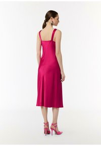 Fuksjowa satynowa sukienka z grubymi ramiączkami, dopasowanym gorsetem i rozkloszowanym dołem. W połączeniu z różowymi sandałami na obcasie z paskami.