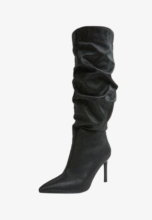 Stivali neri al ginocchio caratterizzati da un design morbido, punta appuntita, tacco a stiletto e ricoperti di piccoli rivetti metallici per una texture unica.