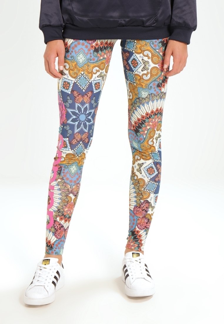 Färgglada mönstrade leggings med intrikata mönster i blått, orange, rosa och vitt, i kombination med vita sneakers.