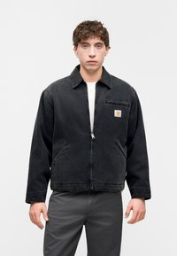 Μαύρο τζιν μπουφάν με εμπρόσθιο φερμουάρ, γιακά με αιχμές και πλαϊνές τσέπες. Διαθέτει μικρό λογότυπο πάνω στην τσέπη του στήθους. Υφασμάτινη υφή.