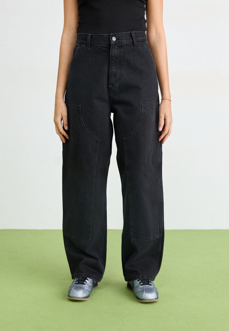Sorte denim vide benbukser med store lommer, høy midje og en ren finish. Kombinert med grå treningssko.