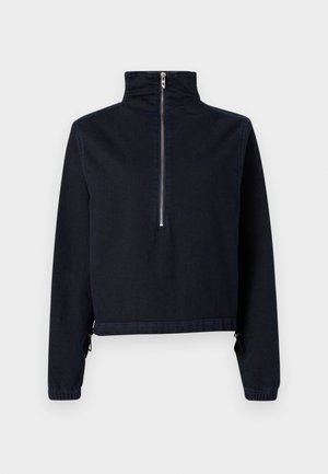 Sötétkék, farmer anyagból készült rövidített dzseki. Magas gallérral, negyedhosszú cipzárral, valamint rugalmas, állítható húzózsinórral ellátott mandzsettákkal rendelkezik.