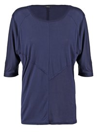 Haut bleu marine avec une coupe décontractée, comportant des manches trois quarts, un col rond et des détails de couture diagonale. Fabriqué en tissu lisse.