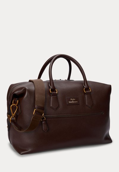 Tumši brūna ādas duffle soma ar diviem rokturiem, regulējamu plecu siksnu, priekšējo rāvējslēdzēja kabatu un Polo Ralph Lauren logotipa plāksteri.