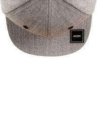Szürke snapback sapka lapos szélekkel, texturált anyagból, fekete téglalap alakú logóval. A felülnézet kiemeli az szerkezetet és a varrást.