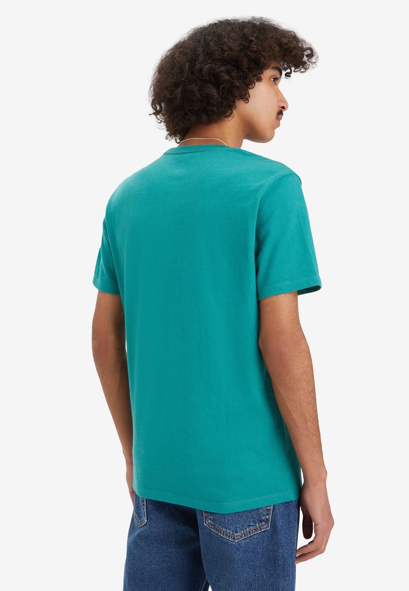Türkises Baumwoll-T-Shirt, kurze Ärmel, Rundhalsausschnitt, einfarbig, lockere Passform, kombiniert mit blauen Jeans, minimalistisches Design.