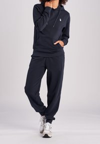 Mörkblå bomullshoodie med en framficka, snoddar och en logotyp. Matchas med joggers i samma färg som har en avslappnad passform och sidfickor.
