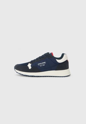 Navy blue sneakers featuring a mix of mesh and suede materials, contrasting white accents, a textured sole, and a prominent brand logo.
