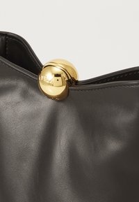 Borsa a mano in pelle nera con accessori in metallo color oro; presenta un grosso gancio rotondo nella parte superiore, una superficie liscia e curve morbide.