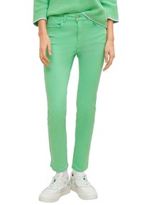 Pantalons en denim vert avec une coupe slim, dotés de poches avant, de passants de ceinture et de détails brodés. Assortis avec des baskets blanches.