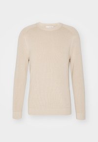 Beige stickad tröja med långa ärmar, rund hals, ribbad textur och en avslappnad passform. Inga synliga mönster eller dekorationer.