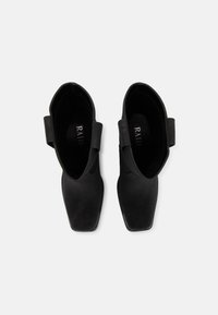 Czarne botki za kostkę o gładkiej fakturze, kwadratowym nosku i elastycznych panelach bocznych. Wewnętrzna wyściółka posiada logo. Smukły i minimalistyczny design.